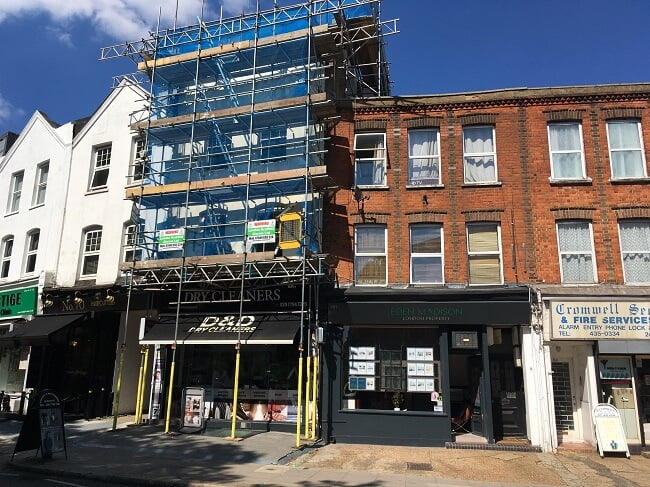 Tall commercial scaffold covered with blue netting