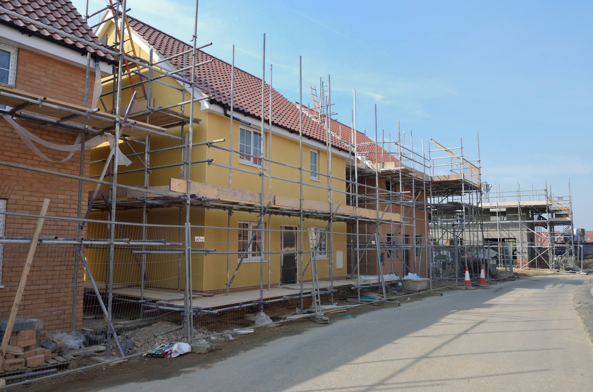 Multiple detached houses in a row covered with scaffolding