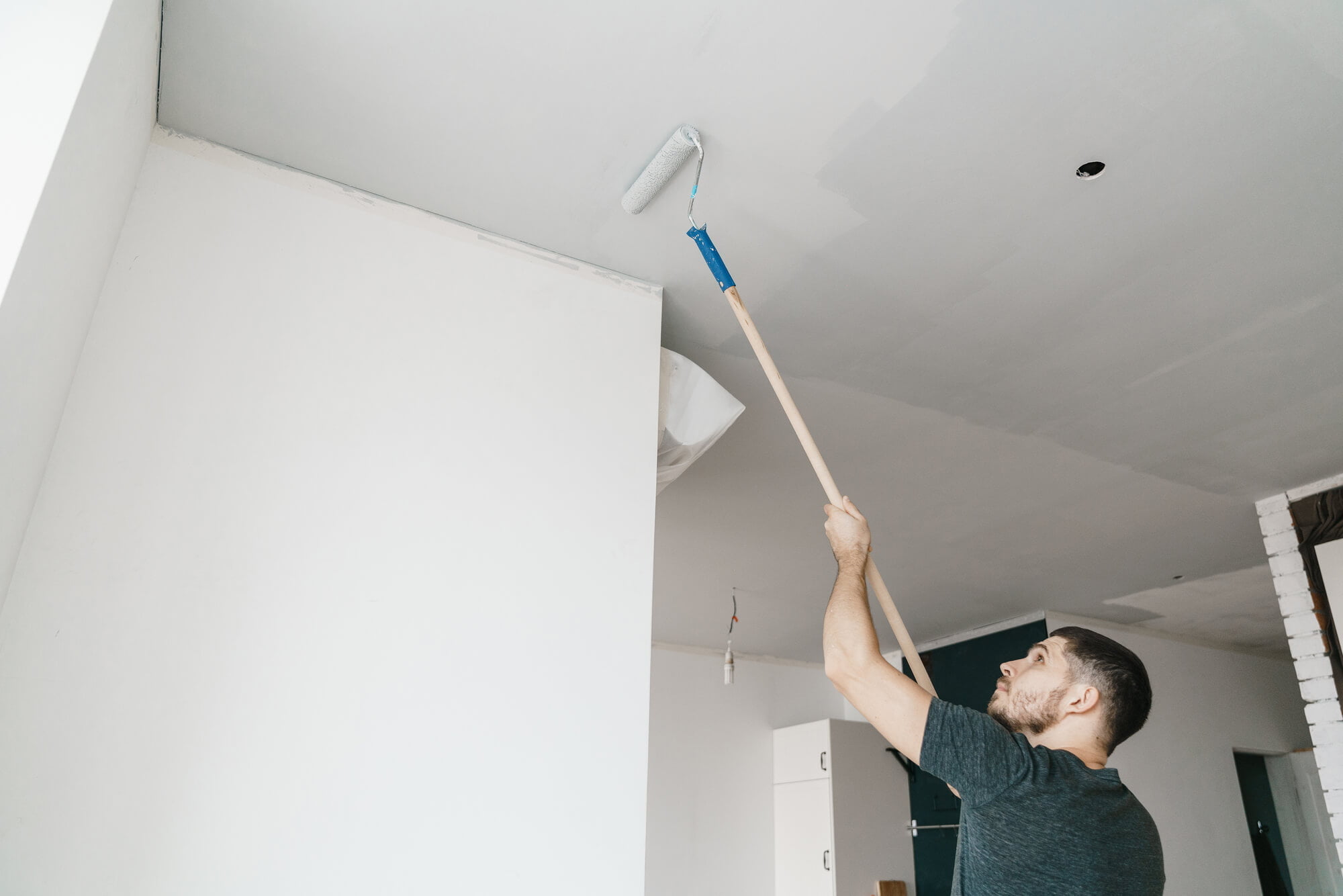 man paint ceiling with extension pole